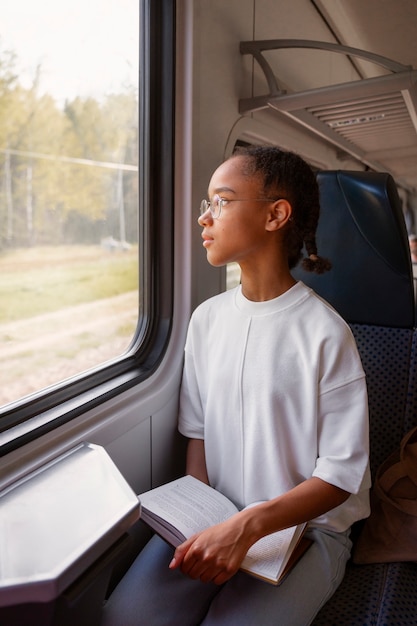 写真 電車の中で本を持つミディアムショットの女の子