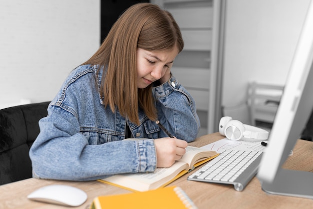 Foto ragazza del colpo medio che scrive in taccuino