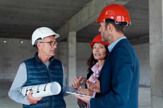 Medium shot of group of caucasian engineers and investors discussing on construction site