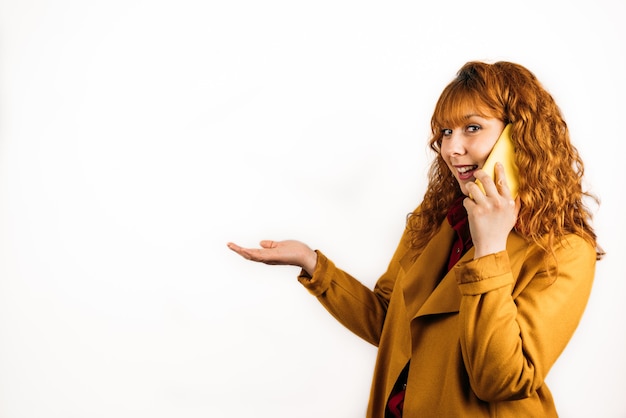 A medium shot of a happy female talking on the phone on an isolated white wall