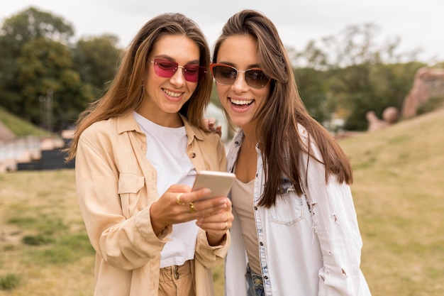 写真 電話を見ているミディアムショットの幸せな女の子