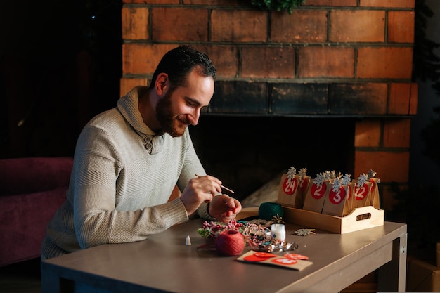 Medium shot of happy young man writing number on red bag making paper bags from kraft paper for