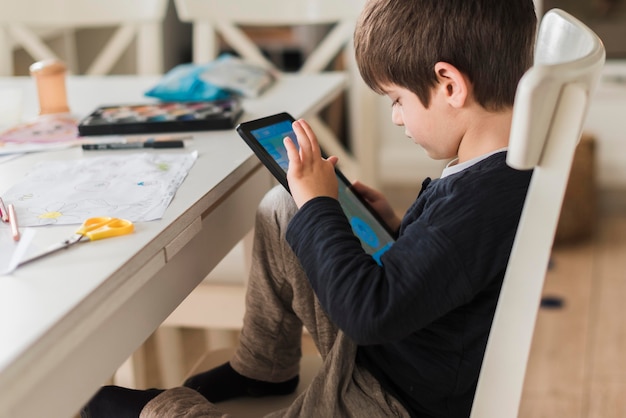 Medium shot kid on chair with tablet