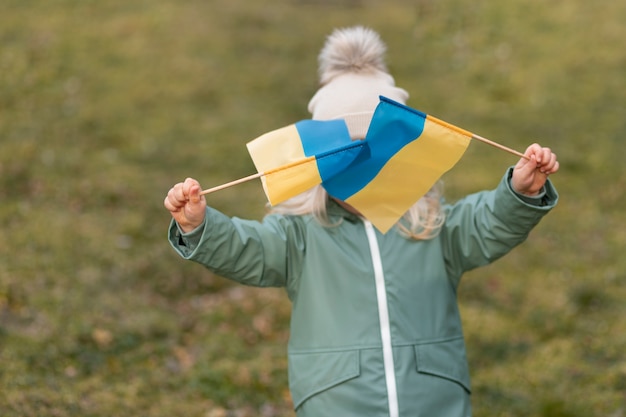 Foto ragazzo di tiro medio che tiene bandiere kraine