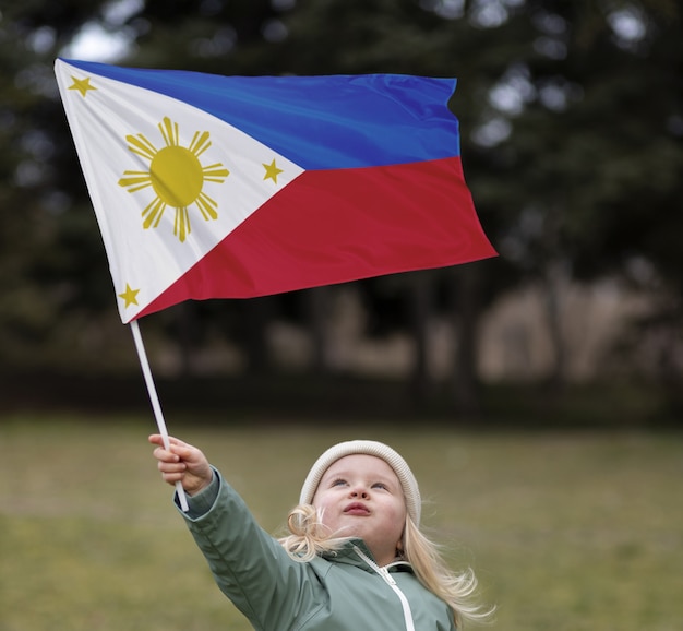 Foto bambino del colpo medio che tiene bandiera filippina