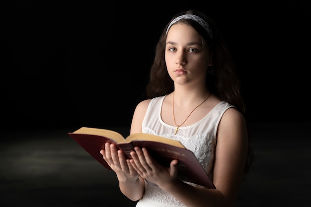 Foto bambino di tiro medio che legge la sacra bibbia