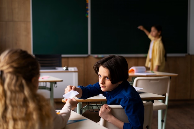 Foto bambino a tiro medio che scrive a bordo