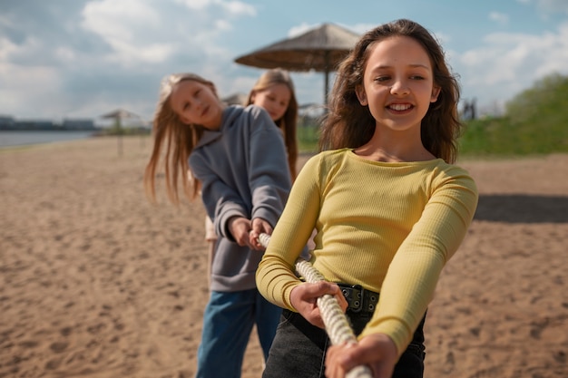 Photo medium shot kids playing tug-of-war on the beach