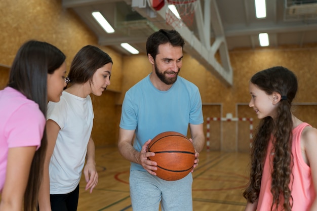 Medium shot kinderen en leraar met basketbal