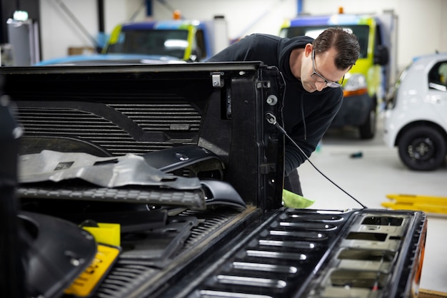 写真 職場で車を掃除するミディアムショットの男