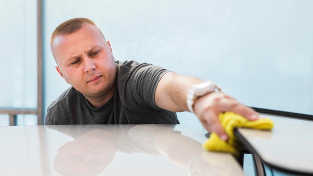 Medium shot man cleaning car with cloth