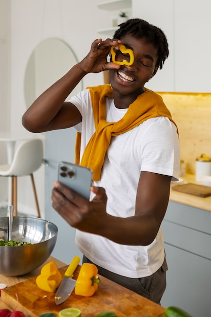 Foto uomo di tiro medio che cucina con lo smartphone