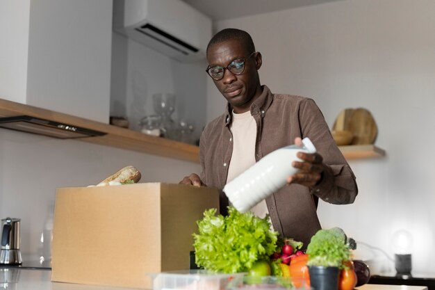 Foto medium shot man die boodschappen uitpakt