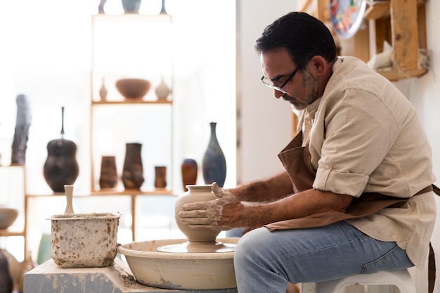 Photo medium shot man doing pottery indoors