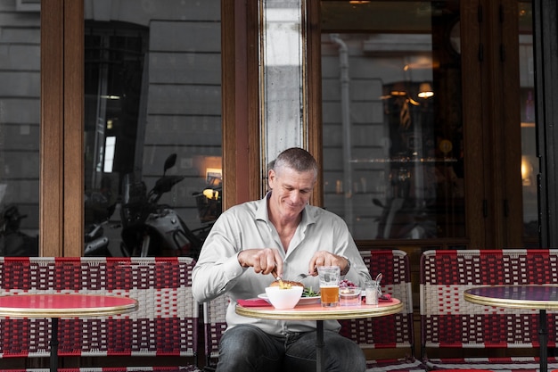 Foto uomo del tiro medio che mangia al bistrot