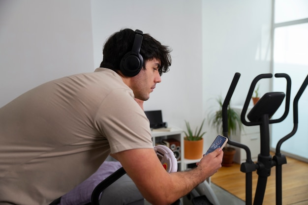 Medium shot man on exercise bike at home