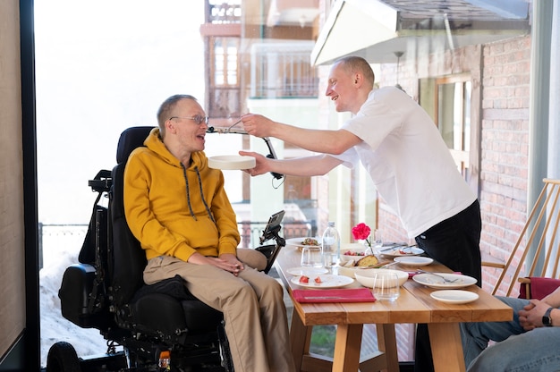 Medium shot man helping disabled friend eat