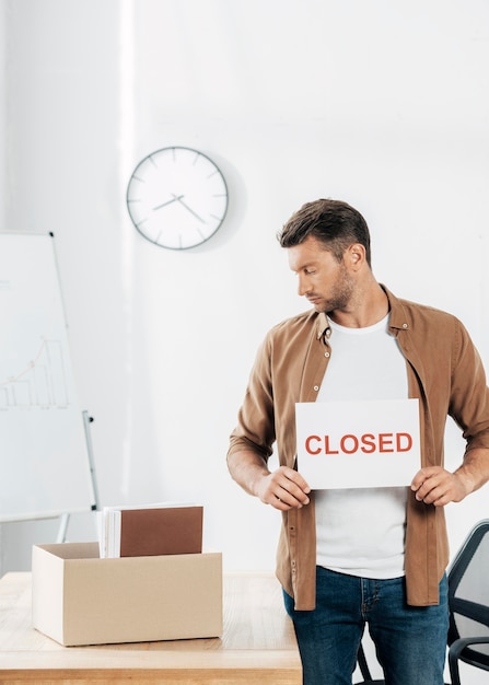 Medium shot man holding closed sign