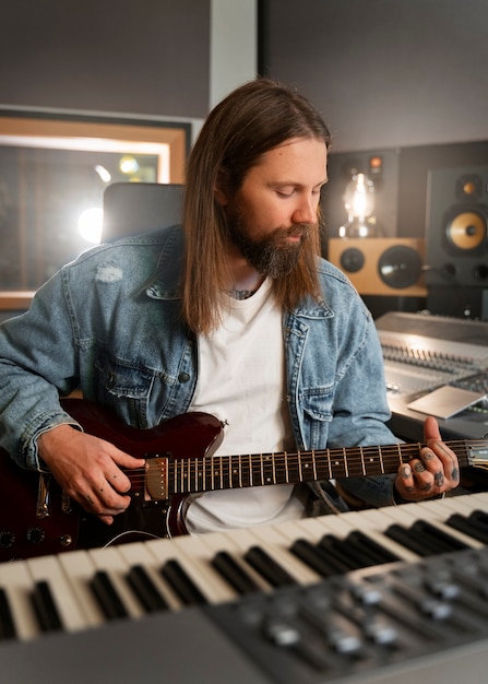 Medium shot man playing the guitar in studio