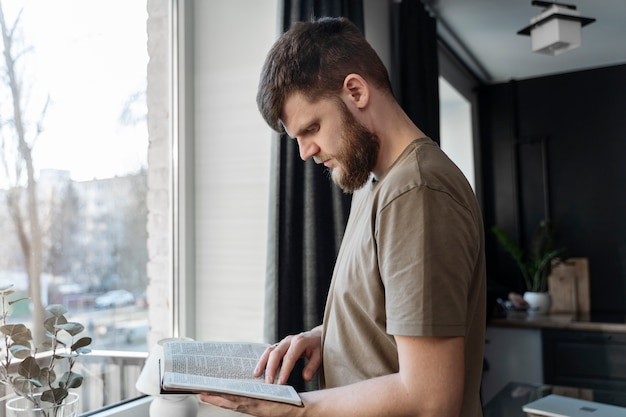 写真 自宅で聖書を読んでいるミディアムショットの男