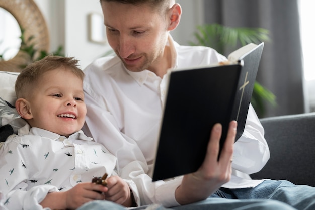 Photo medium shot man reading bible to son