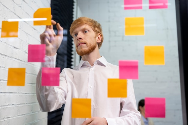 medium shot man sticking post it at work