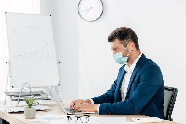 Uomo del colpo medio che digita sul computer portatile