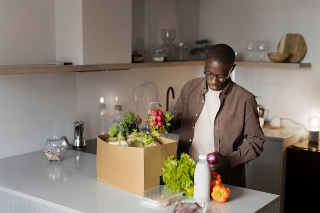 写真 自宅で食料品を開梱するミディアムショットの男