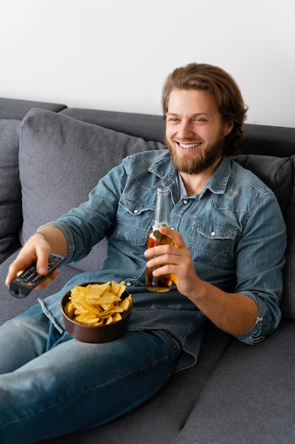 Uomo di tiro medio che guarda la tv a casa