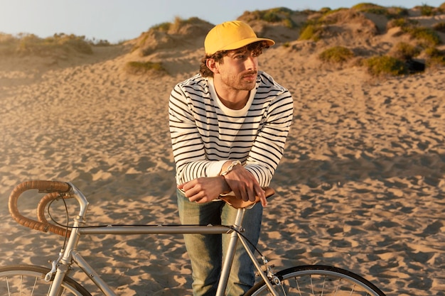 Foto uomo di tiro medio con bici in riva al mare