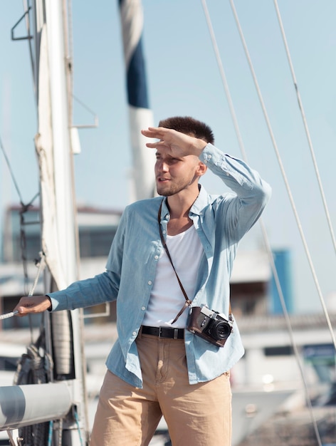 Foto uomo del colpo medio con la macchina fotografica che osserva via