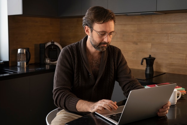 Uomo del tiro medio che lavora al computer portatile