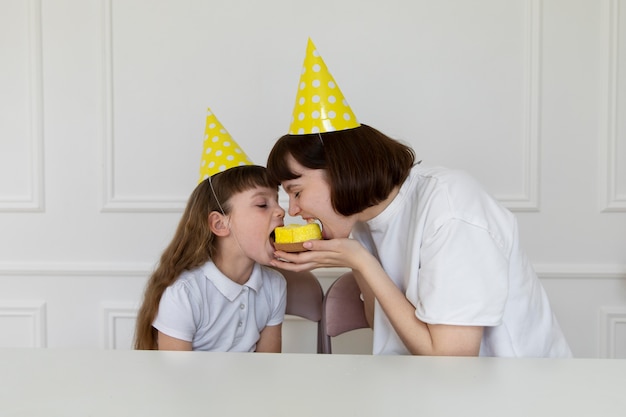 Photo medium shot mother and girl eating cupcake