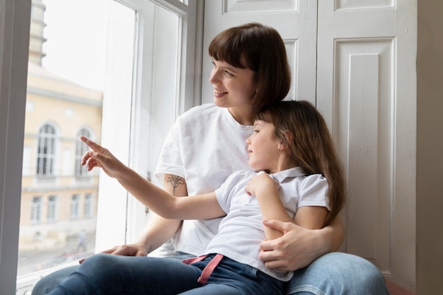 Photo medium shot mother and girl looking out the window