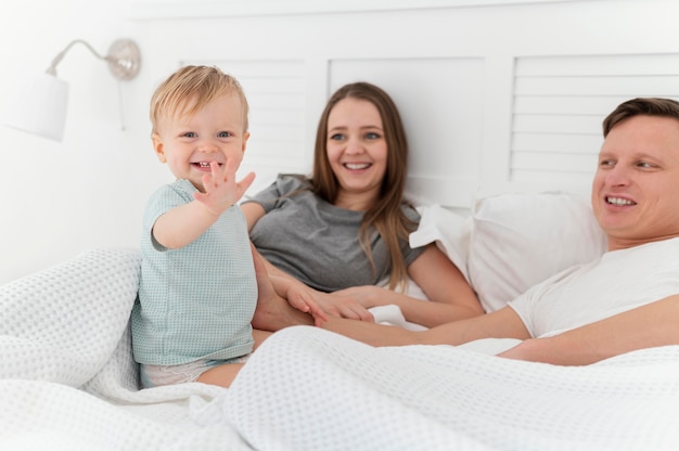 Средний снимок родителей с ребенком в постели