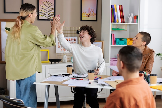 Medium shot people high five at work