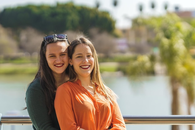 Medium shot of a portrait of lesbian couple embracing and smiling at the camera