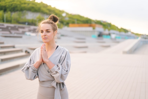 Medium shot portret van meditatieve blanke jonge vrouw die yoga beoefent die namaste pose uitvoert