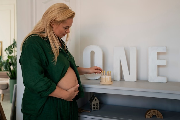 Фото Средняя беременная женщина проводит время в помещении.