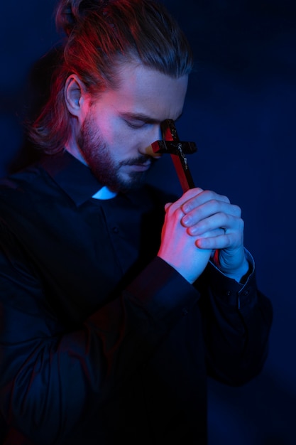 Medium shot priest praying with cross