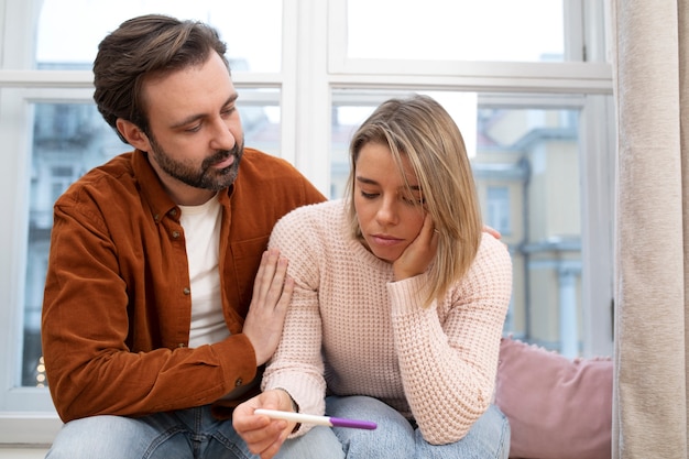 Photo medium shot sad couple looking at pregnancy test