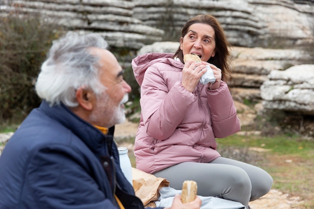 Foto persone anziane di tiro medio che mangiano in natura