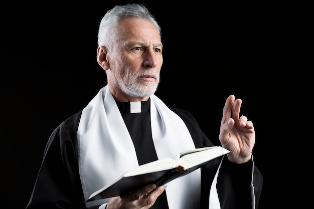 Medium shot senior priest preaching with bible