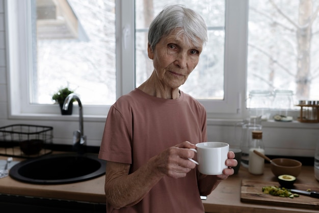 写真 コーヒーカップを保持しているミディアムショットの年配の女性