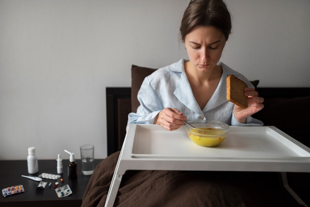 Donna malata a colpo medio che mangia zuppa