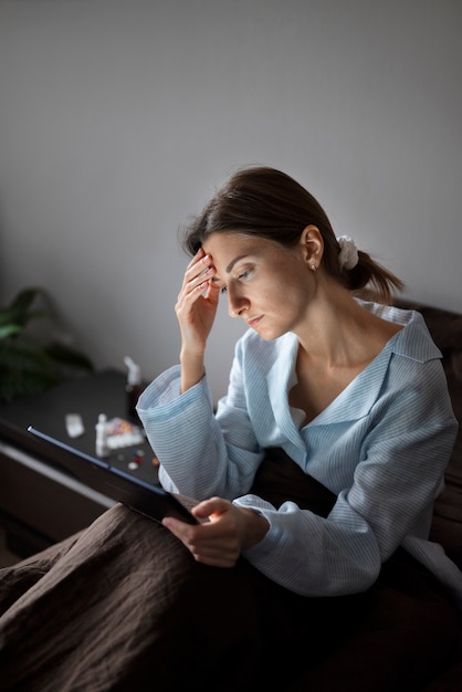 Photo medium shot sick woman holding tablet