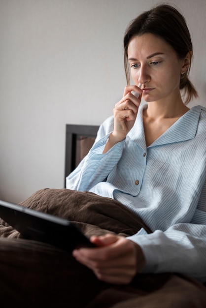 Medium shot sick woman holding tablet