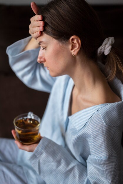 写真 お茶とミディアムショットの病気の女性