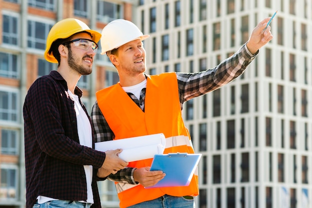 Medium shot side view of engineer and architect looking at building