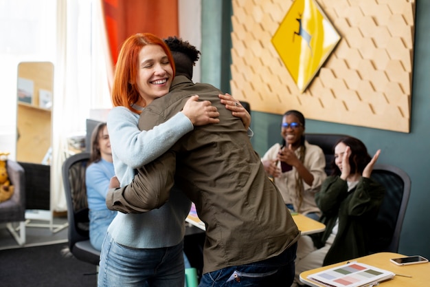 Medium shot smiley collega's knuffelen op het werk